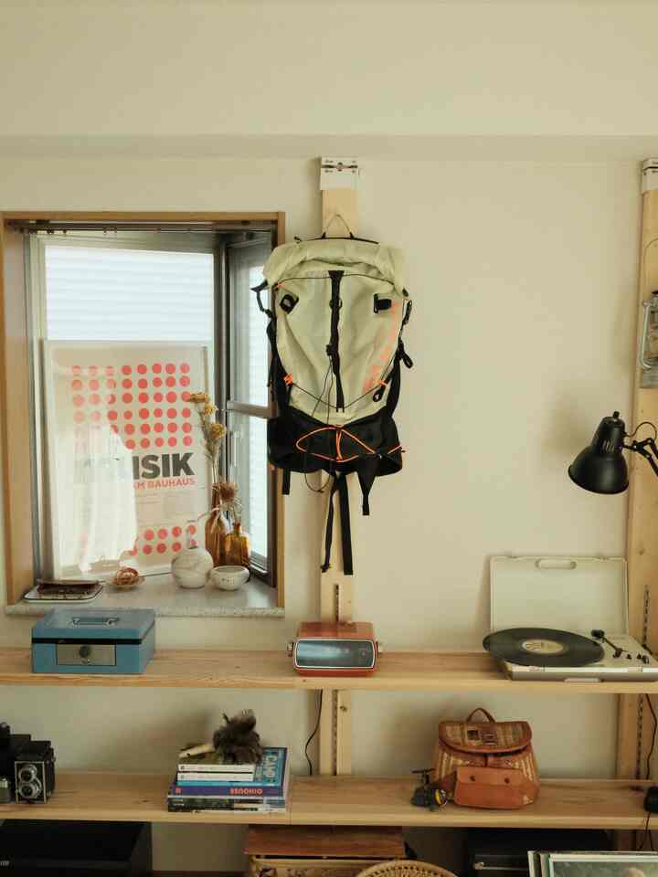 ナチュラルカラーのワンルーム空間、レトロな小物や壁照明が配置された散らかった雰囲気の部屋