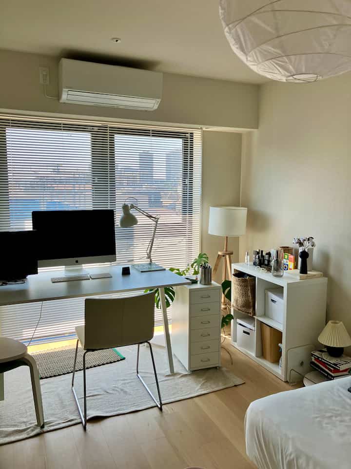 Bright white and wood tone 2K bedroom featuring desk, chair, bookshelf, creating a tidy home office space