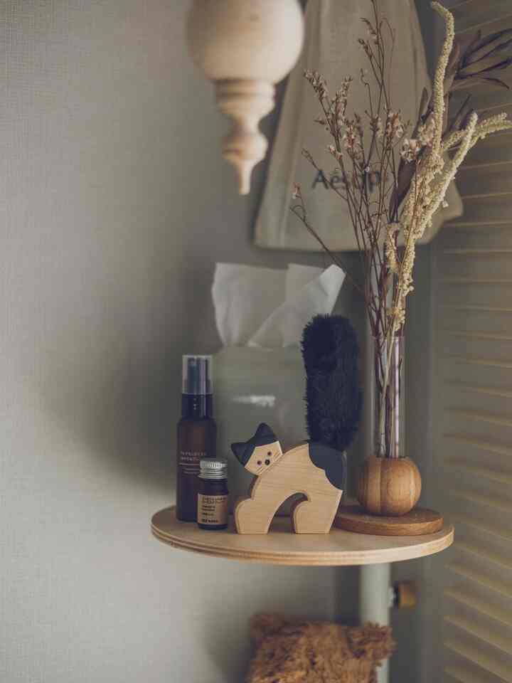 ナチュラルな木目調の小さな棚に猫のオブジェとドライプラント、ディフューザーが配置された雰囲気のある空間