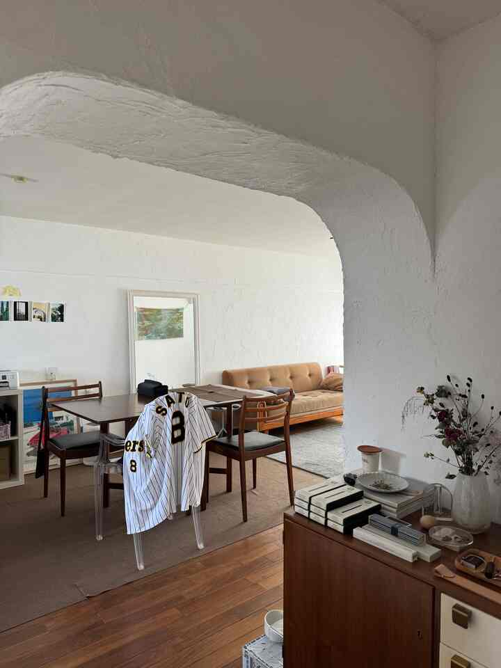 ナチュラルカラーとブラウン調のリビング・ダイニング空間、アーチ型の壁と快適なソファが配置された温かみのあるインテリア