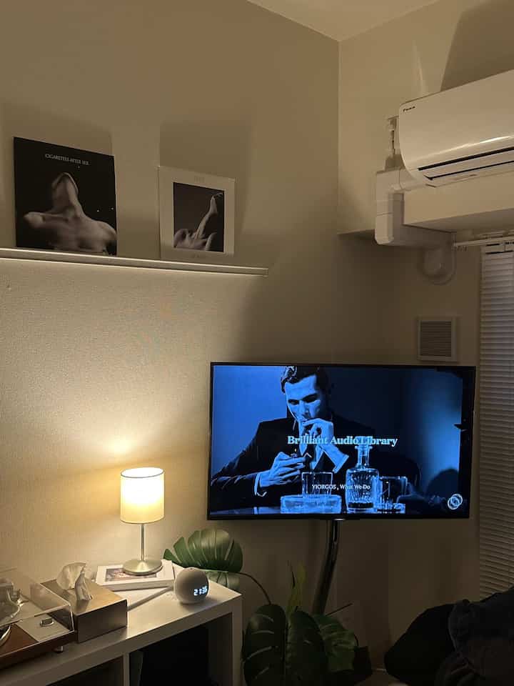 Black and white toned small living room featuring a TV stand and floor lamp with a modern, simple atmosphere