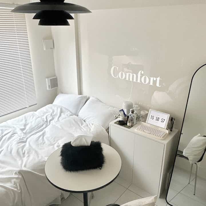 ホワイトトーンの寝室、整ったベッドとナイトテーブルが配置されたミニマルでモダンなインテリア