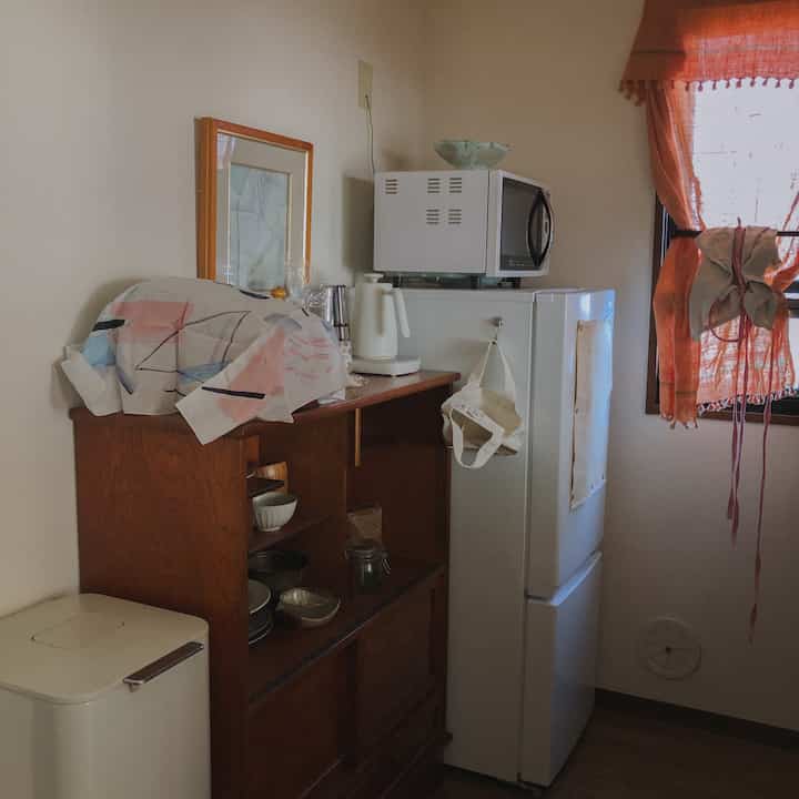 ブラウンの木目調と白の家電が配置された温かみのあるキッチン、キッチンタオルと食器が置かれた雰囲気のあるインテリア