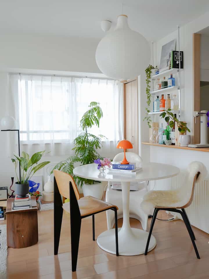 Bright dining room in white and wood tones featuring a round dining table with mixed chairs, creating a natural and airy atmosphere