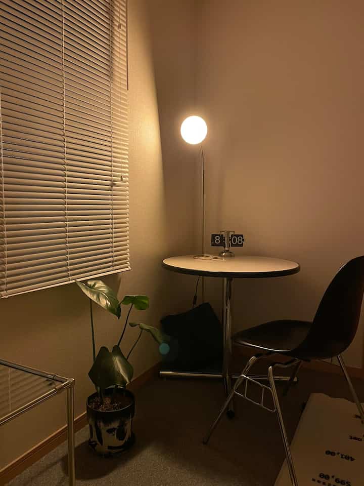 Small room in white and black tones featuring round dining table, chair, floor lamp, and plant in a modern Art Deco style