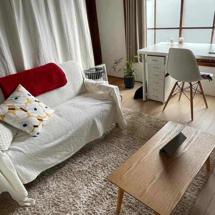 An 8畳 white and natural tone room featuring a compact sofa and desk arranged in a cozy setting
