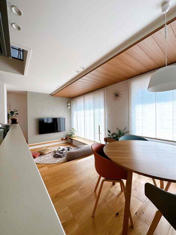 白と木目調のリビングダイニング、窓際ベンチとビーンバッグソファが配置された自然な雰囲気の空間