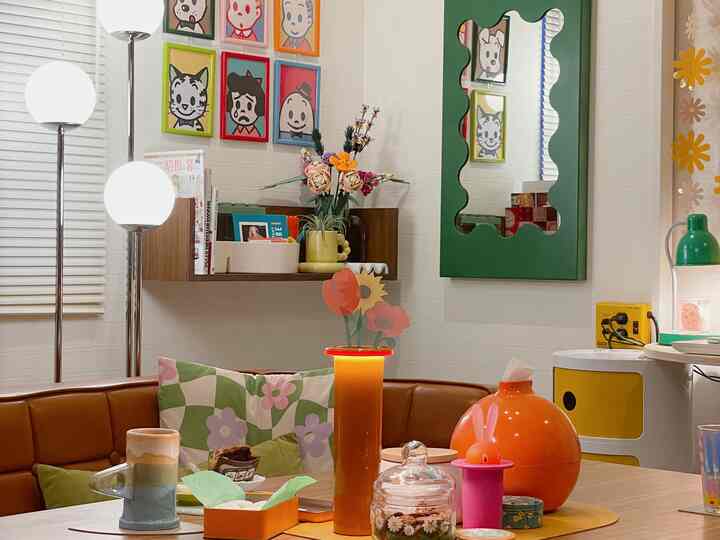 Natural-tone cozy living room featuring brown sofa, colorful patterned cushions, vibrant wall art, and a large green mirror