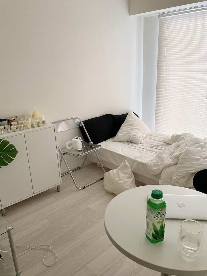 A white and natural color-toned small 1K bedroom for a single household, featuring minimal furniture and clean blinds