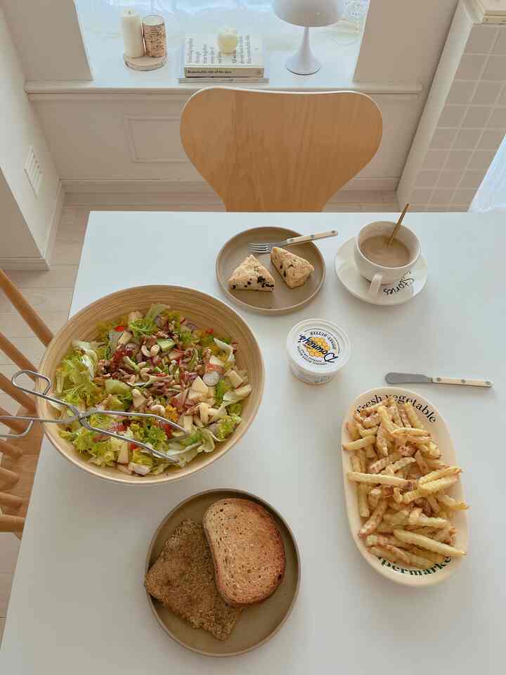 ナチュラルカラーとホワイトが調和するダイニング、木製の椅子と色々な皿が並ぶブランチの空間