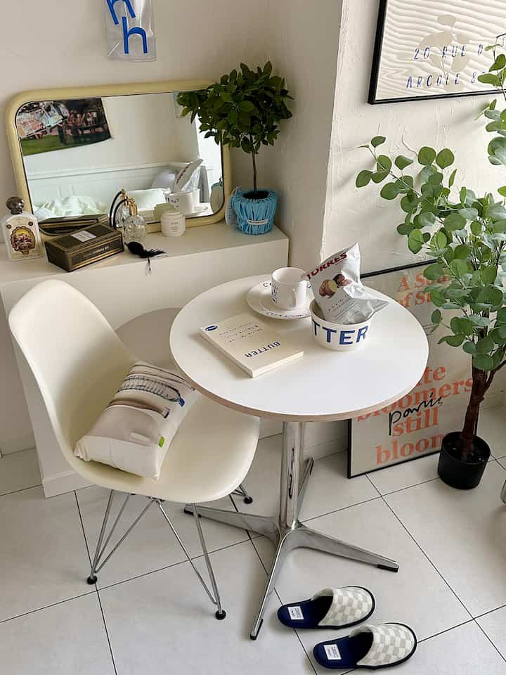 Natural white and wood tone small living room with round table, chair, and plants in a minimalist setting