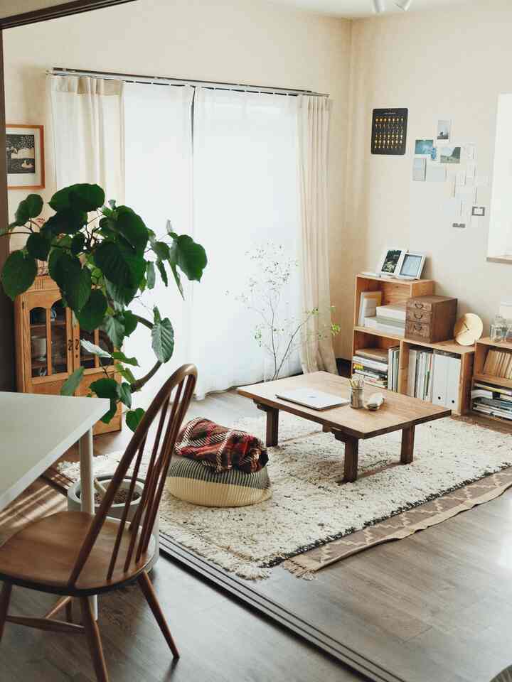 Beige and brown toned living room featuring a wooden table and plush cushion at center with cozy natural modern style