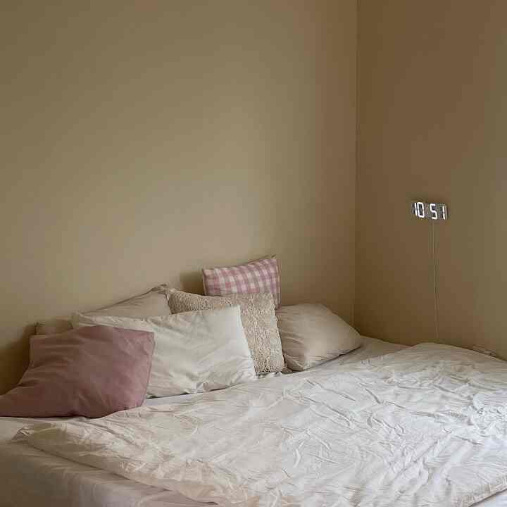 ベージュの壁と白い寝具が配置されたシンプルな寝室のインテリア