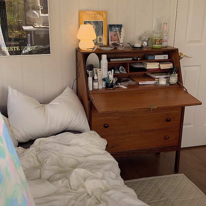 白い寝具と木目調のドレッサーが配置された温かみのある寝室のインテリア