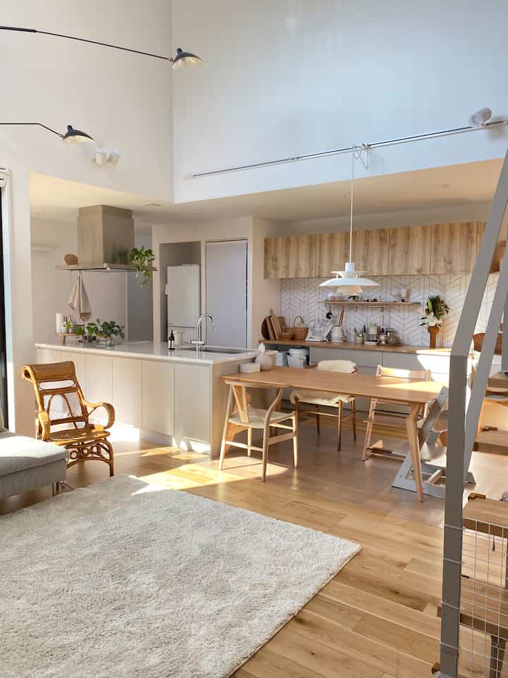 明るいホワイトトーンのリビングとキッチン、ナチュラルな木製ダイニングテーブルが配置された落ち着いた空間