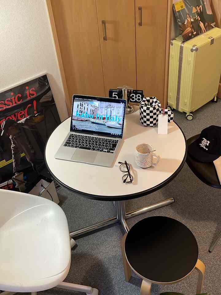 白と黒の色調のコンパクトなワンルーム、円形のテーブルにノートパソコンやスツールが配置された雰囲気のあるおうちカフェ空間