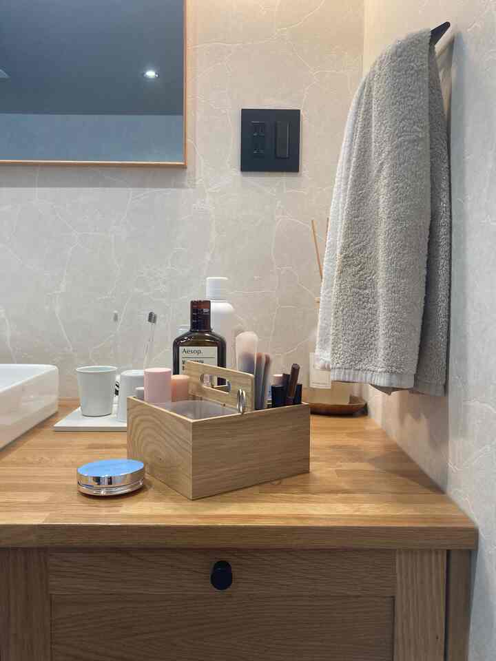 ナチュラルな木目調と白を基調としたパウダールームの化粧台、無印良品の木製収納ボックスと整頓されたコスメが配置された印象的な空間