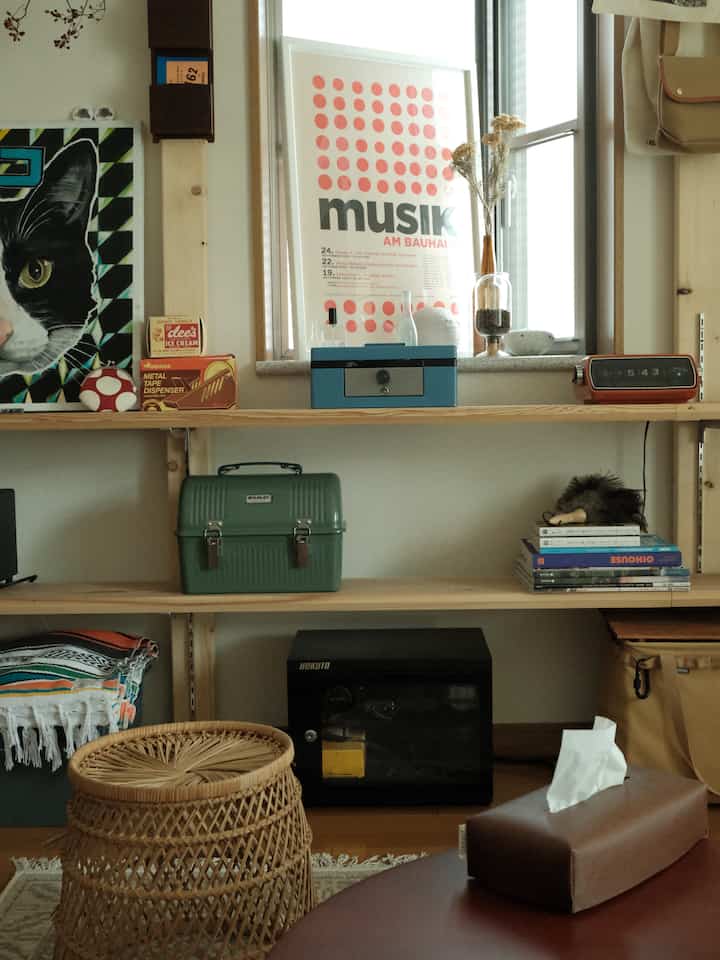 Natural-toned living space featuring wooden shelves with diverse storage items, framed art, and decorative objects creating a harmonious interior