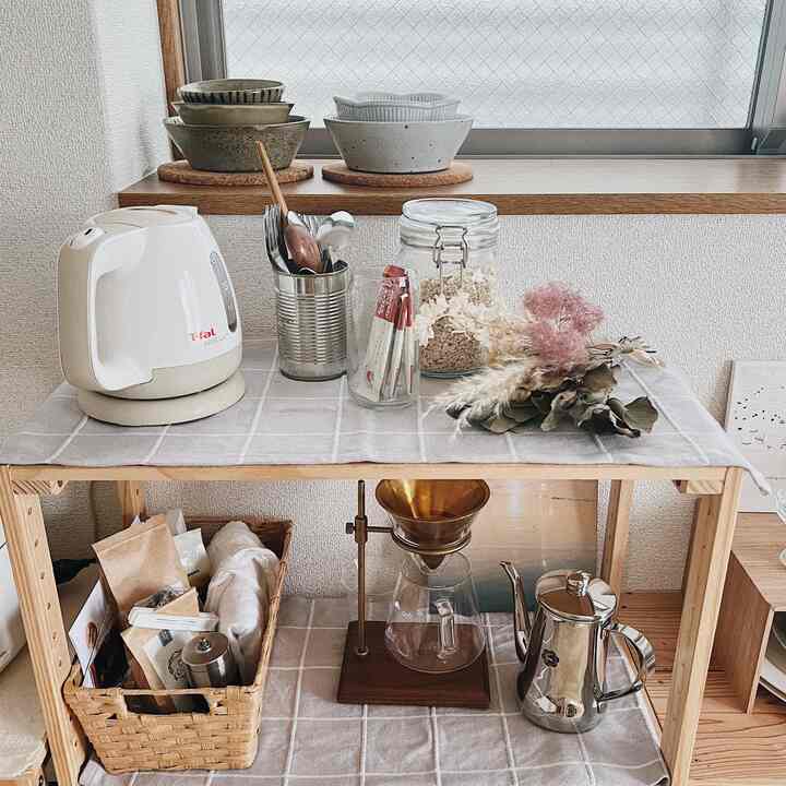 Natural wood tones and beige hues in a kitchen space; wooden shelves neatly arranged with coffee tools and storage containers in a cozy home cafe style