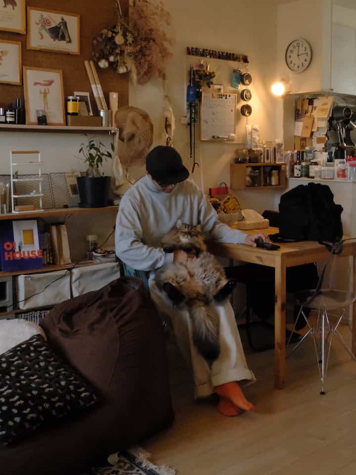 ベージュとナチュラルカラーのリビング、ビーンバッグソファとダイニングテーブルが配置された居心地の良い空間、猫と暮らす様子