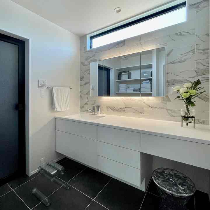 白とグレー調のバスルーム洗面スペース、ホテルライクな雰囲気の洗面台と鏡が配置されたモダンな空間