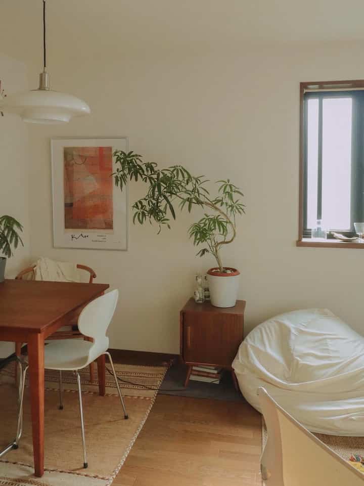 ホワイトと木目調のダイニングルーム、ダイニングテーブルと植物、ビーズクッションが配置された雰囲気のあるインテリア