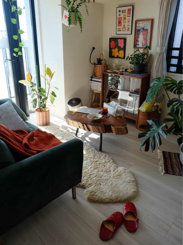 緑と茶色のトーンが調和したリビング、ウッドのコーヒーテーブルとグリーンソファが配置された自然で温かみのあるインテリア