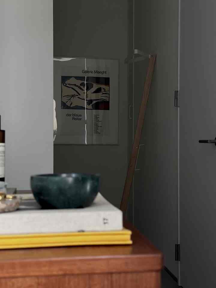 木目調と白い壁の玄関、シンプルなコートハンガーとアートポスターが配置された雰囲気あるインテリア