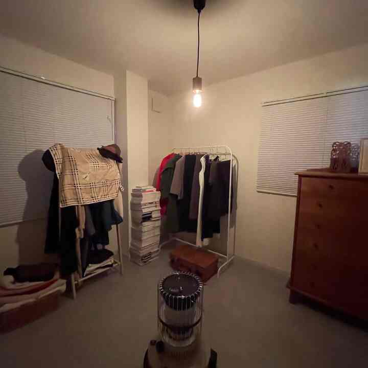 白い壁と茶色の家具が配置されたナチュラルな雰囲気のウォークインクローゼット、穏やかな照明が空間を照らす