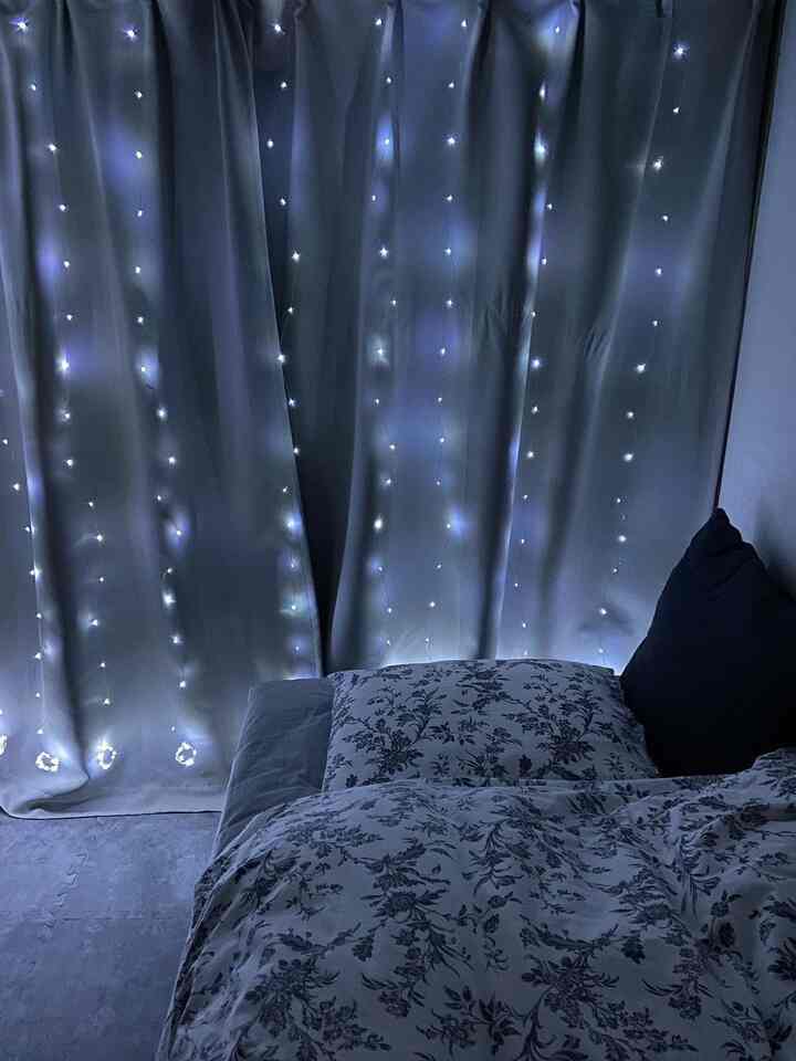 Blue and white toned bedroom featuring patterned bedding and string lights, creating a cozy winter ambiance