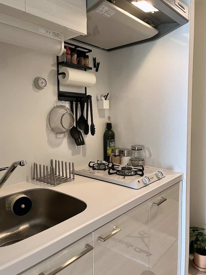 Minimal kitchen in white and gray tones with efficient wall-mounted storage, creating a clean and compact space