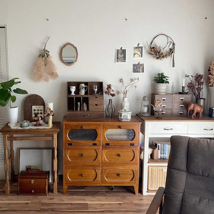 ナチュラルなブラウン調のリビング、ヴィンテージの収納キャビネットと額縁が配置された印象的な空間