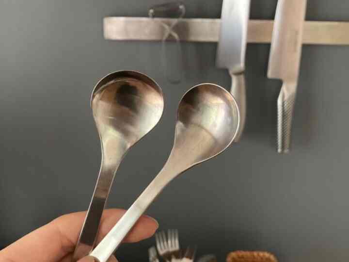 ダークグレーの壁にシルバーのスプーンと包丁が掛けられたキッチン、洗練されたモダンな雰囲気のインテリア