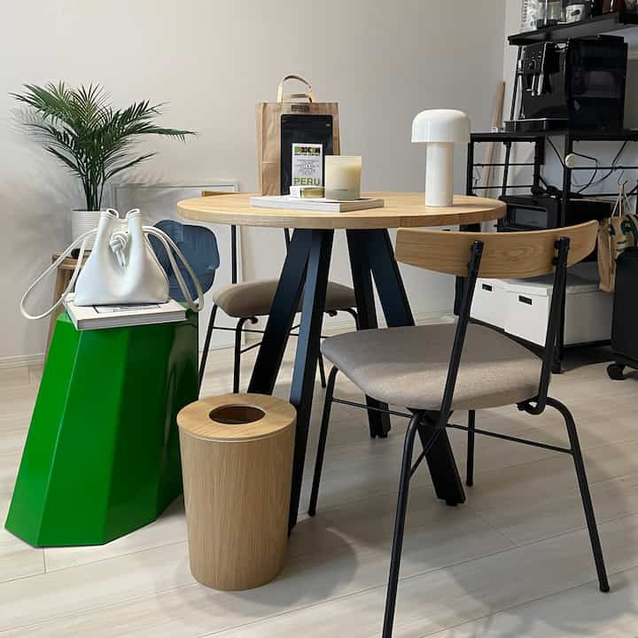 Natural wood tones and white blend in a cafe-style dining space featuring a round wooden table, dining chairs, and a home cafe setup with coffee machine