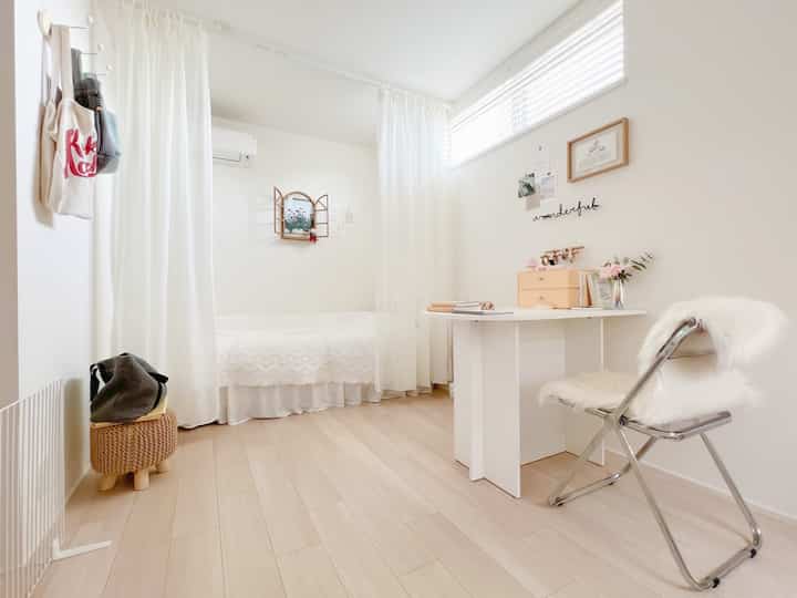 Bright white and natural tone compact bedroom featuring a simple desk and bed with a cozy atmosphere