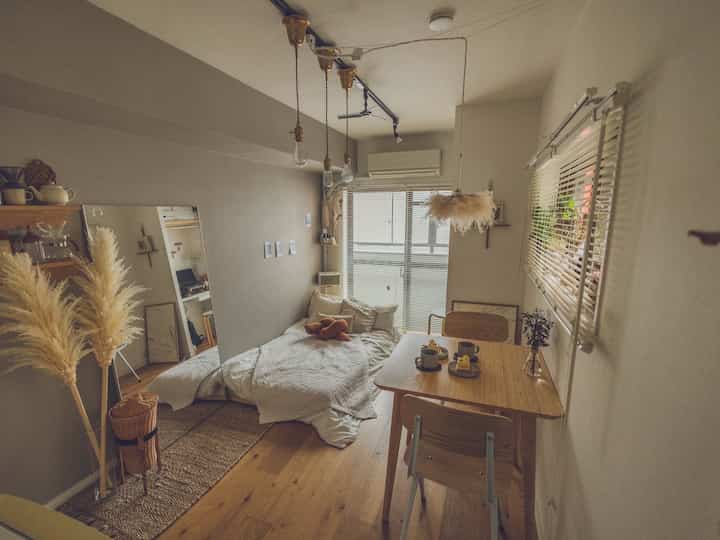 Natural brown and white toned studio apartment featuring a bed and dining table arranged for cozy living