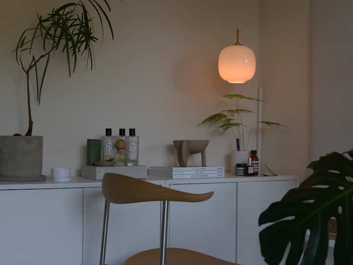 ホワイトとウッドトーンのリビング、ペンダントライトと植物が配置された雰囲気のあるシンプルなカフェ風インテリア