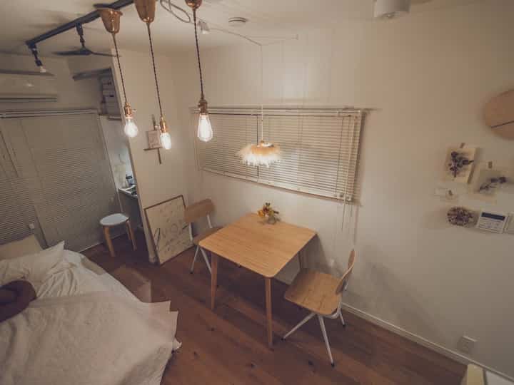Warm orange-toned studio bedroom featuring a wooden table and chair creating a cozy atmosphere
