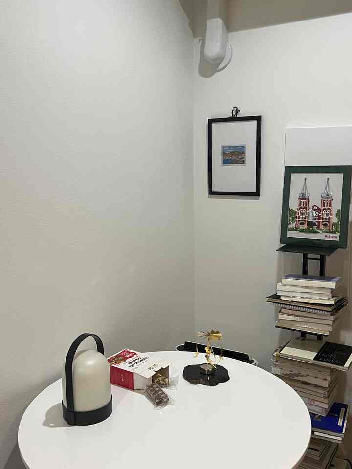 White-toned small room with a round coffee table and tower shelf stacked with books, creating a minimalistic space