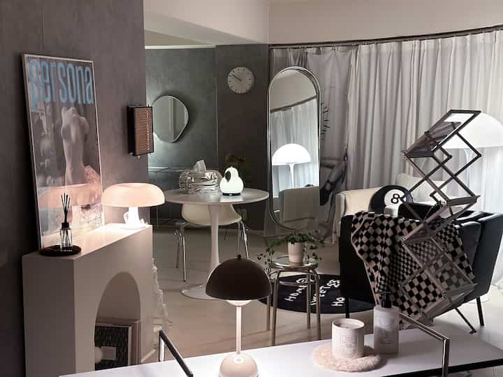 チャコールとホワイトの色調のリビング、ミッドセンチュリーモダンの家具と大きなシルバーの鏡が配置された洗練された落ち着いたインテリア