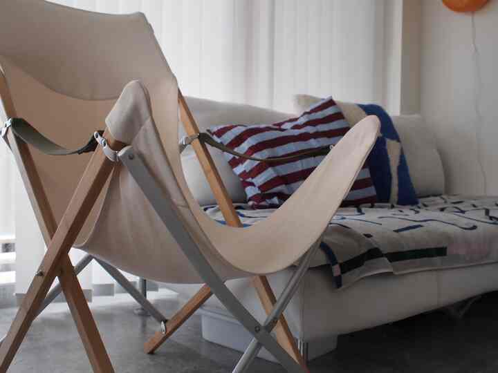 A minimalist living room with white and natural wood tones featuring a Snowpeak outdoor chair and a clean sofa