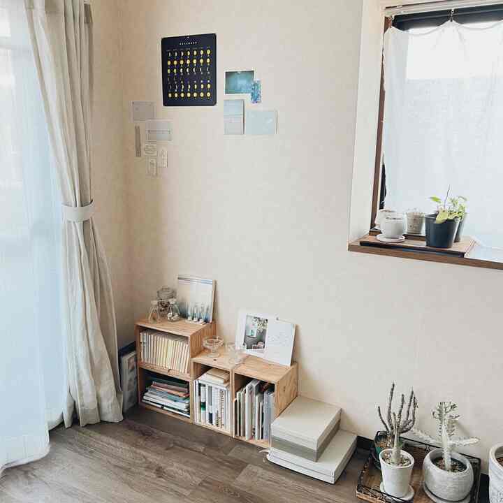 ナチュラルカラーの小さなリビングコーナー、低い家具と本棚が配置された落ち着いた印象的な空間