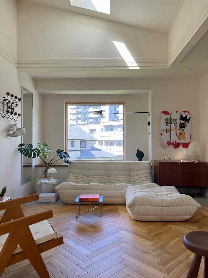 A natural modern living room with dominant white and wood tones, featuring a comfortable sofa and abundant natural light through the window