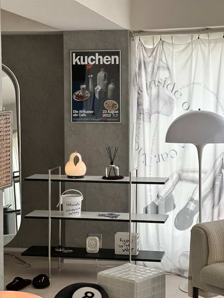 Modern living room in white and black tones featuring a shelf and a poster creating a tidy atmosphere