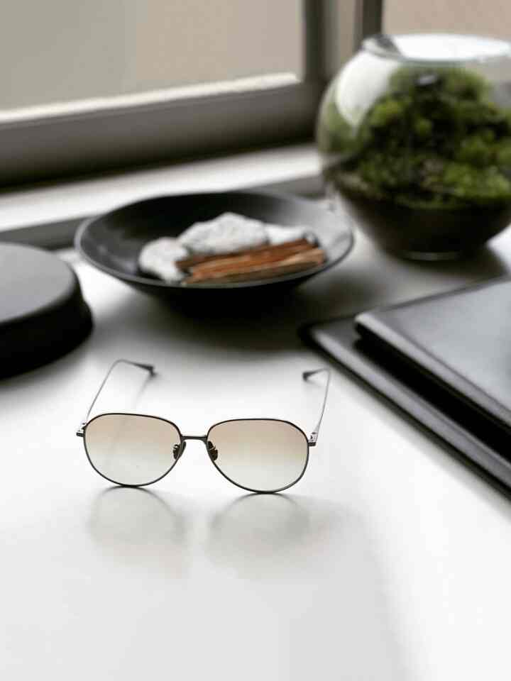 白いテーブルの上に緑のテラリウムと黒い皿が配置されたミニマルな空間