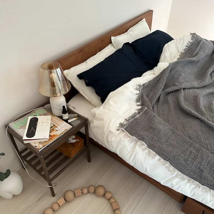 A bedroom with a harmonious blend of white and wood tones, featuring pillows and a blanket on the bed creating a calm atmosphere