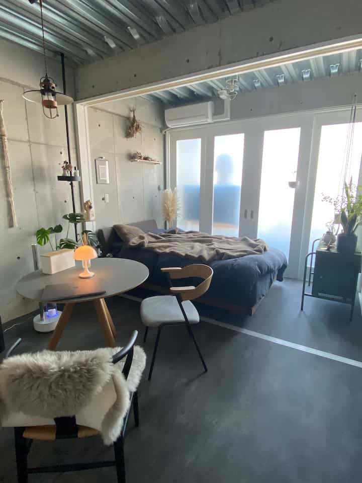 Charcoal and natural color modern studio bedroom featuring wooden table and plants in a warm atmosphere