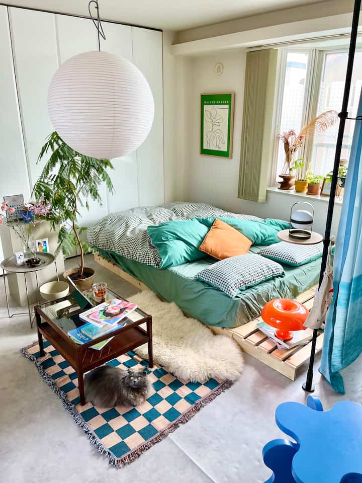 White and green toned bedroom featuring a compact wooden bed and plants, creating a natural and simple atmosphere