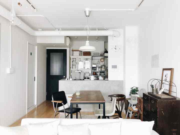 Simple living room in white and wood tones featuring a wooden dining table with assorted chairs in a modern space