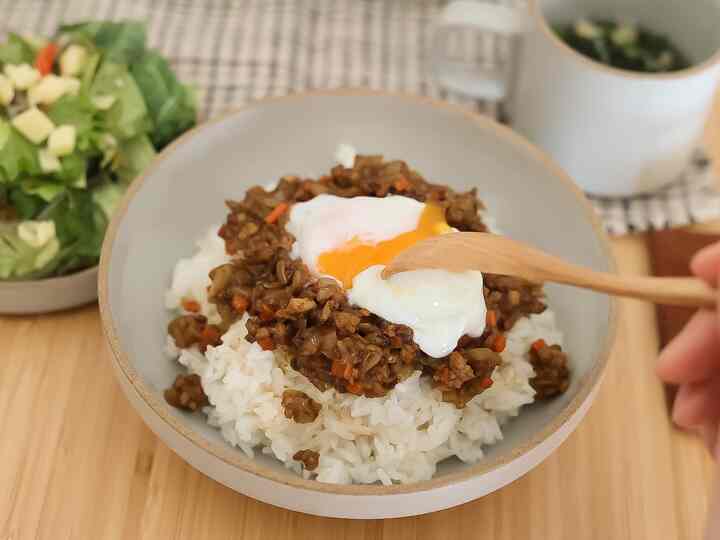 ナチュラルな色調のキッチンテーブルにハサミポーセリンのボウル、キーマカレーと半熟卵、木のスプーンが置かれた雰囲気のあるおうちカフェの食事風景